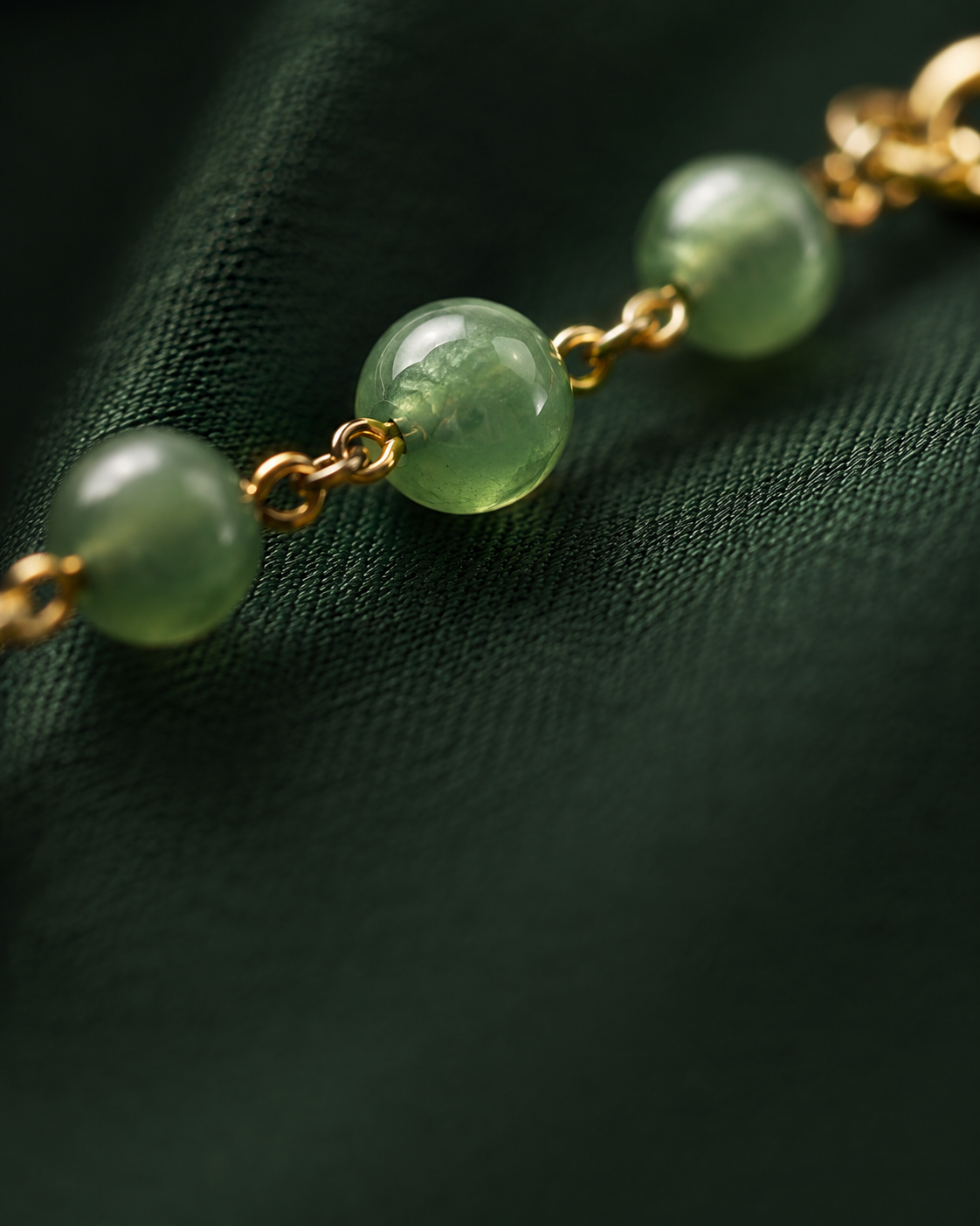Macro detail of a gold-plated chain and green stone bead