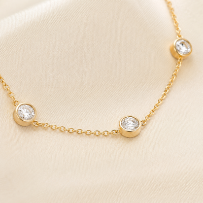 Close-up of round bezel-set cubic zirconia stations on a gold-plated necklace